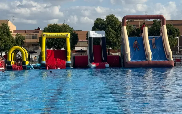 Niños deslizandose por los toboganes hinchables instalados en la piscina María Luisa Cabañero