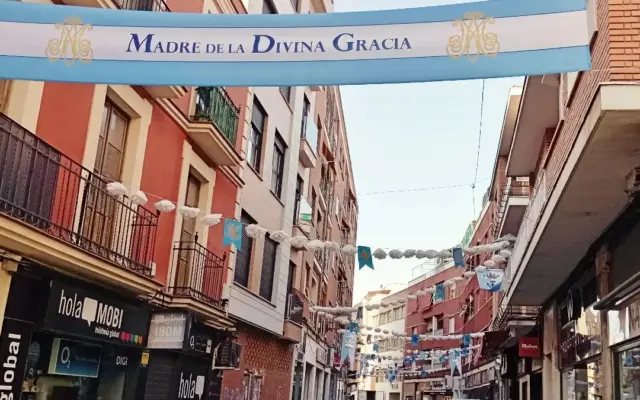 Guirnaldas de flores de papel decorando la calle Calzada a su paso por la Virgen de Gracia
