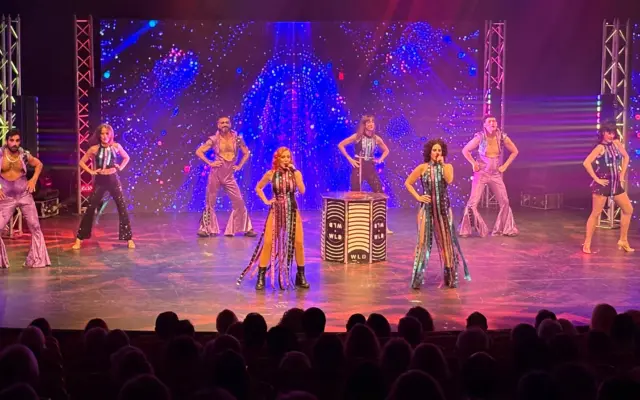 Cantantes y bailarines del musical We Love Disco actuando en el escenario del Auditorio Municipal Pedro Almodóvar de Puertollano, con luces de ambiente discoteca